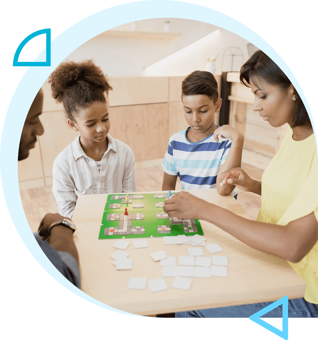 A mother and two children playing a board game at a table.