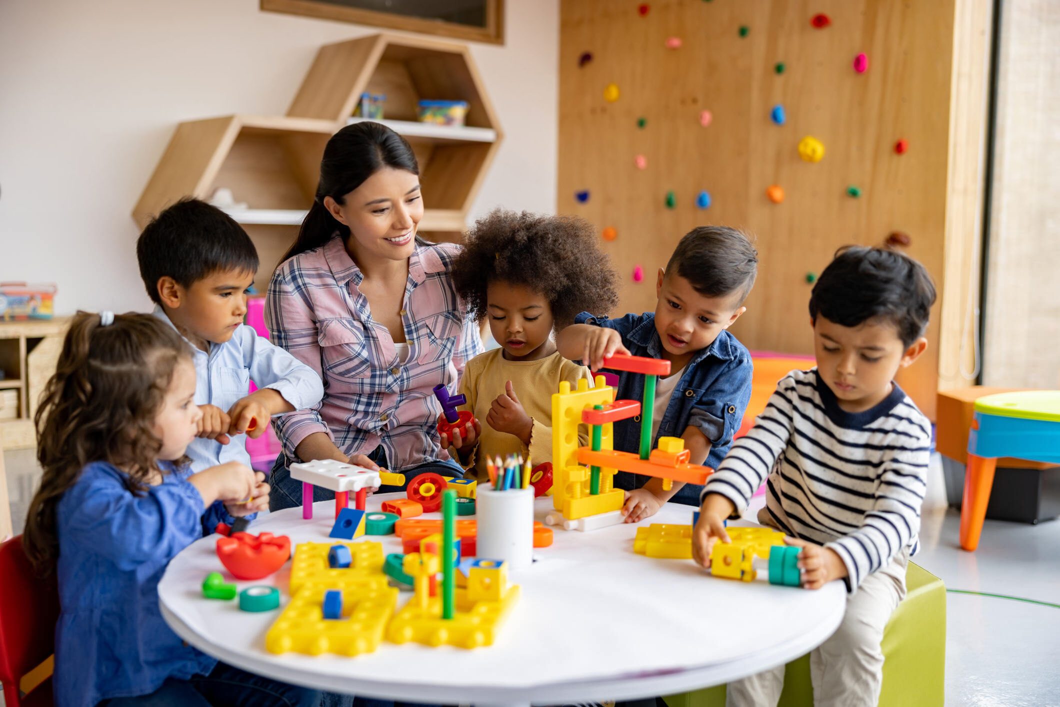 Children and a teacher playing with colorful building blocks.
