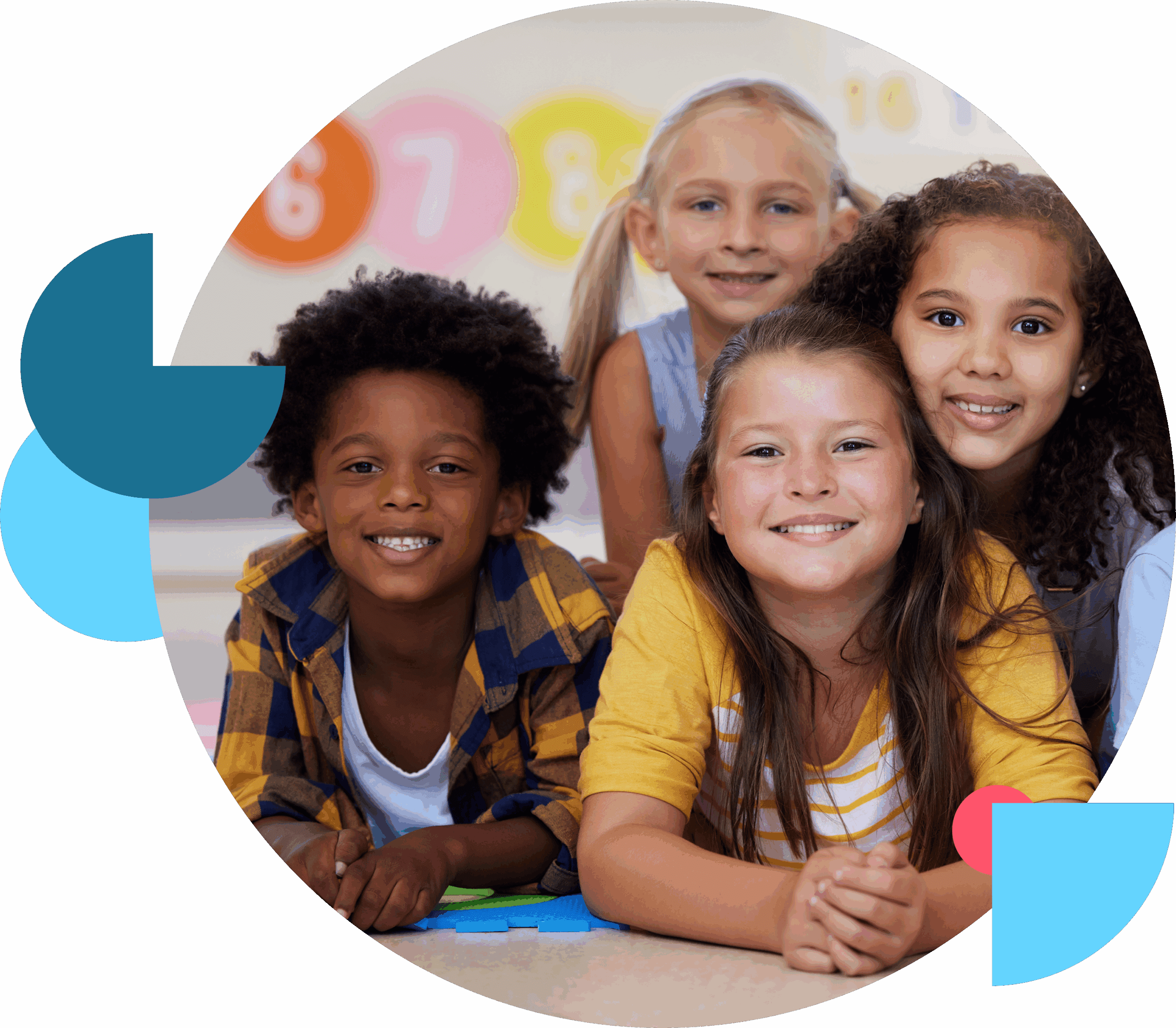 Four diverse children smiling and lying on the floor in a classroom.