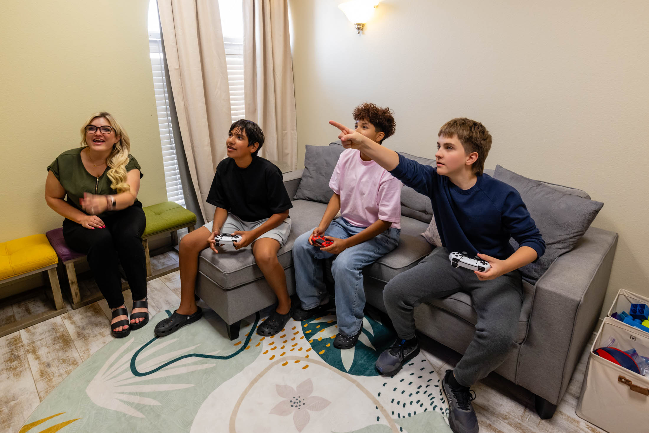 Four young people enthusiastically play video games in a cozy living room.